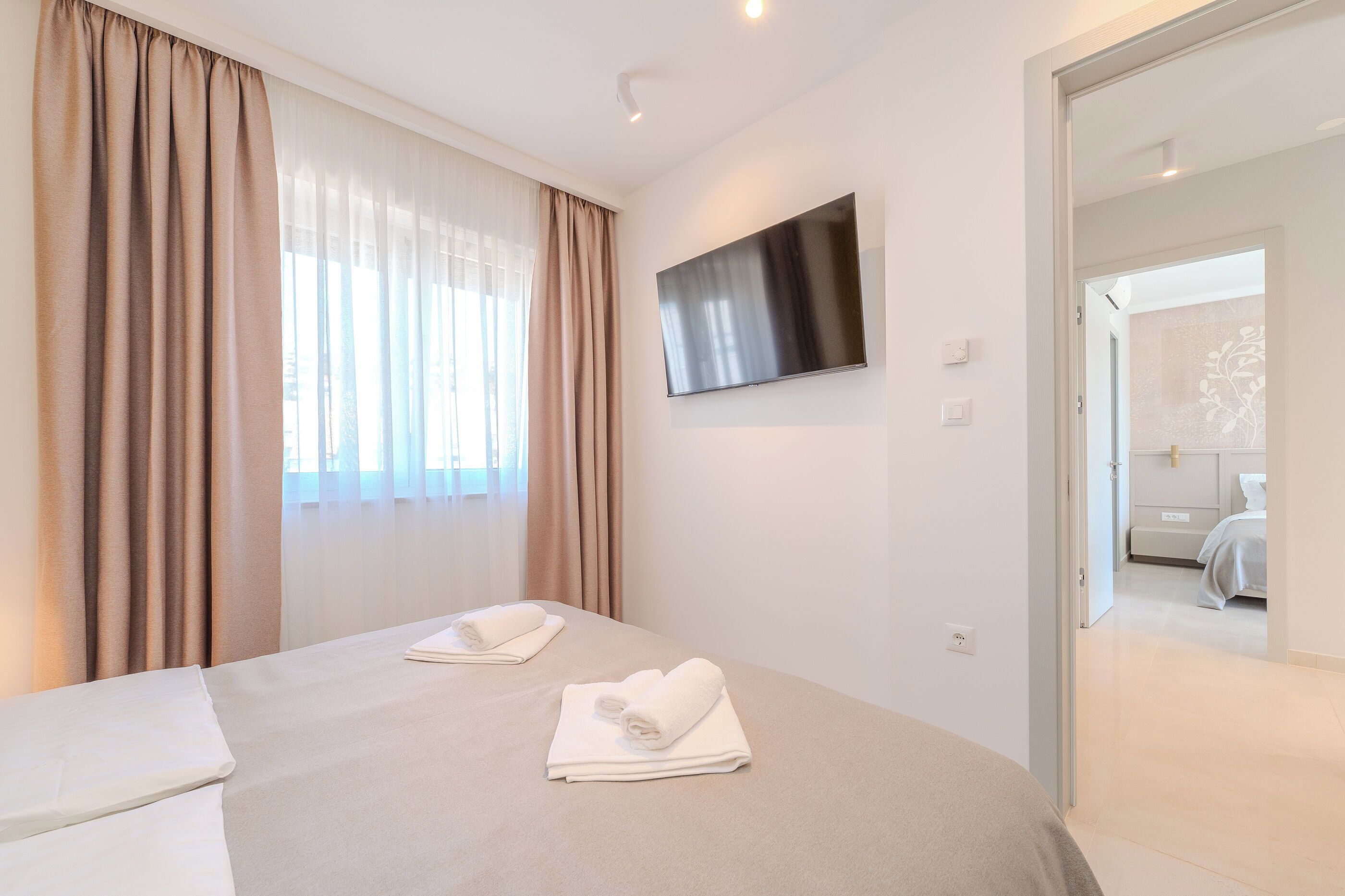 A hotel room with a bed, two towels, a TV, and a door leading to a bathroom.