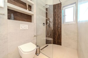 A modern bathroom with a glass-enclosed shower, a toilet, and a vanity with a mirror. - Villa Nexi by old Town (Sibenik)