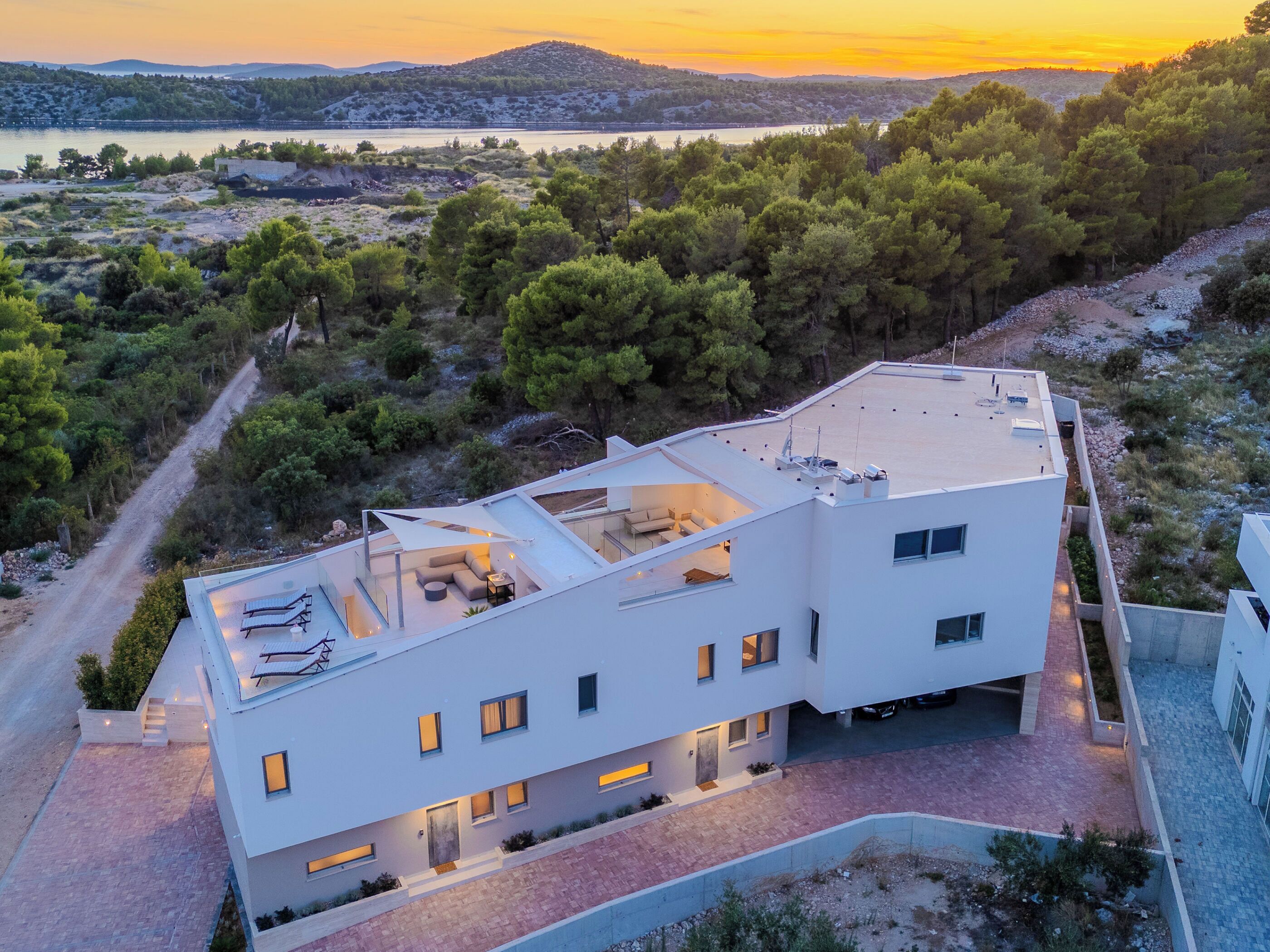 Un immeuble moderne à plusieurs étages, doté d’un toit plat, de grandes fenêtres et d’une terrasse sur le toit avec des espaces de détente en plein air.