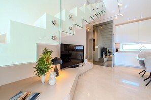 Ein modernes Wohnzimmer mit Fernseher, Pflanze und Essbereich mit Tisch und Stühlen.