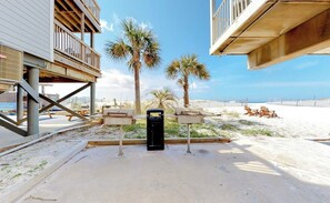 Ein strandnahes Anwesen mit einer Holzterrasse, Palmen und einem Sandstrand.