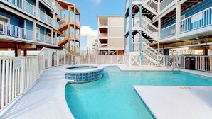 Un espace piscine avec un jacuzzi, entouré d’immeubles à plusieurs étages dotés de balcons.