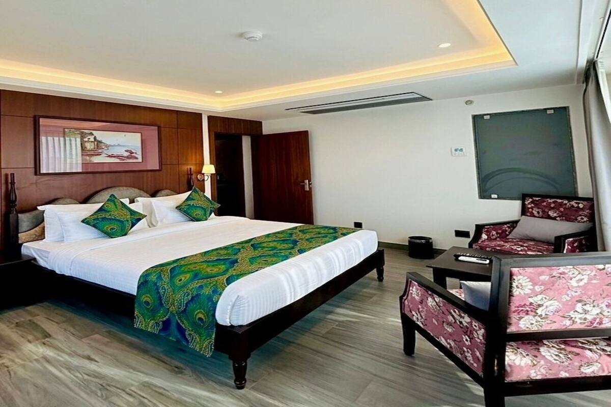 Ein Hotelzimmer mit einem Bett, einem Schreibtisch, einem Stuhl und einem Gemälde an der Wand.