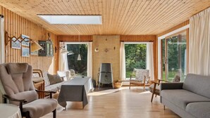 Ein geräumiges Wohnzimmer mit Holzwänden, einem großen Tisch, Sofas und einem Kamin.