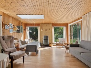 A spacious living area with wooden walls, a large table, and comfortable seating. - 4 Star Holiday Home in Follenslev (Follenslev)