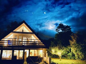 A house with a triangular roof, large windows, and a well-lit interior. - 4 Star Holiday Home in Follenslev (Follenslev)