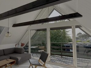 A modern loft bedroom with a large skylight, a gray sofa, a wooden chair, and a small table. - 4 Star Holiday Home in Follenslev (Follenslev)