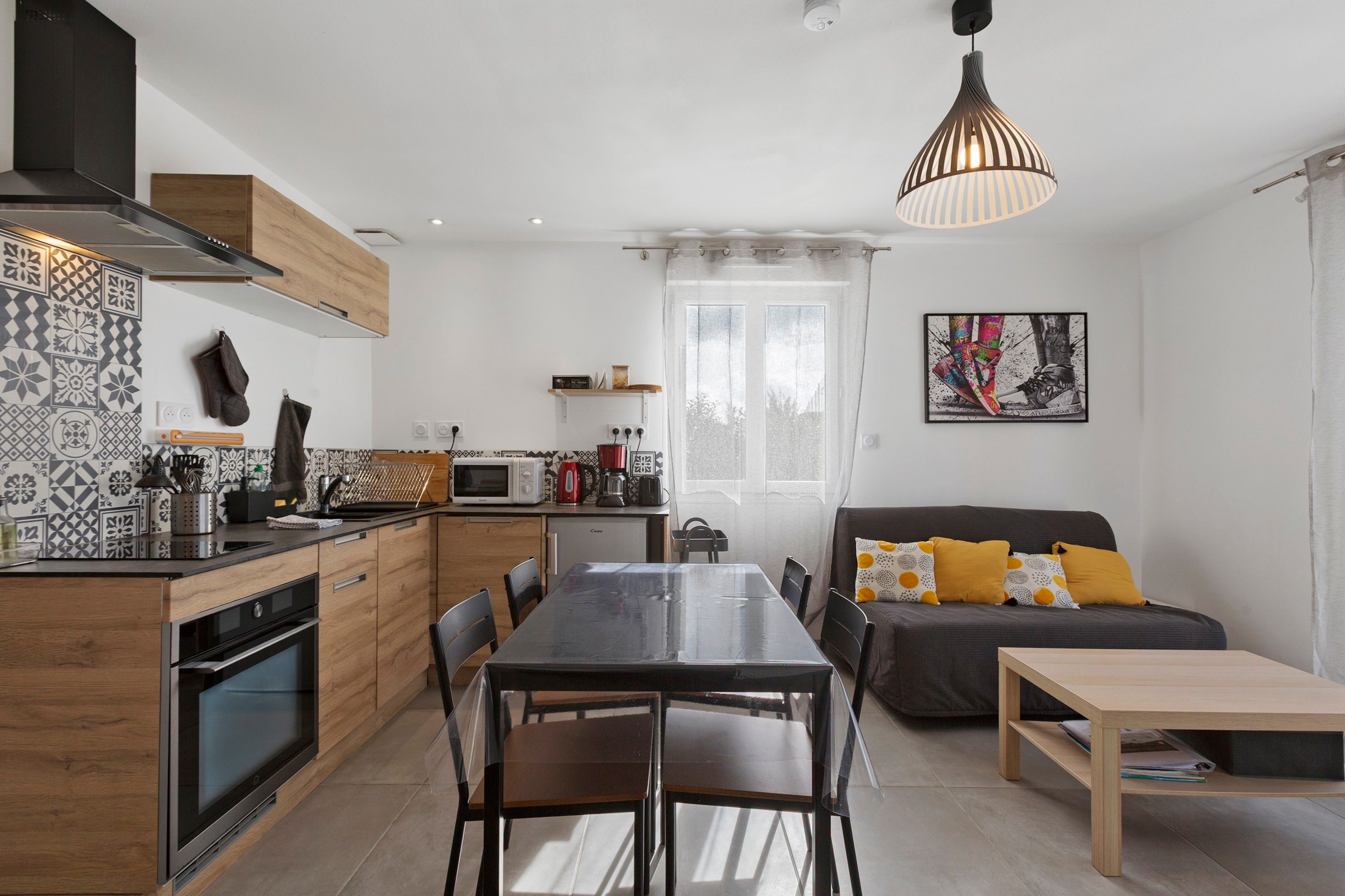 Une cuisine moderne avec un coin repas, un canapé avec des coussins et un tableau au mur.