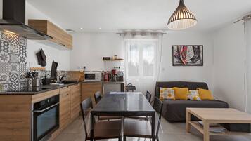 Une cuisine moderne avec un coin repas, un canapé avec des coussins et un tableau au mur.