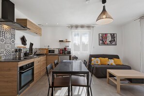 Una cocina moderna con comedor, un sofá con cojines y un cuadro en la pared.