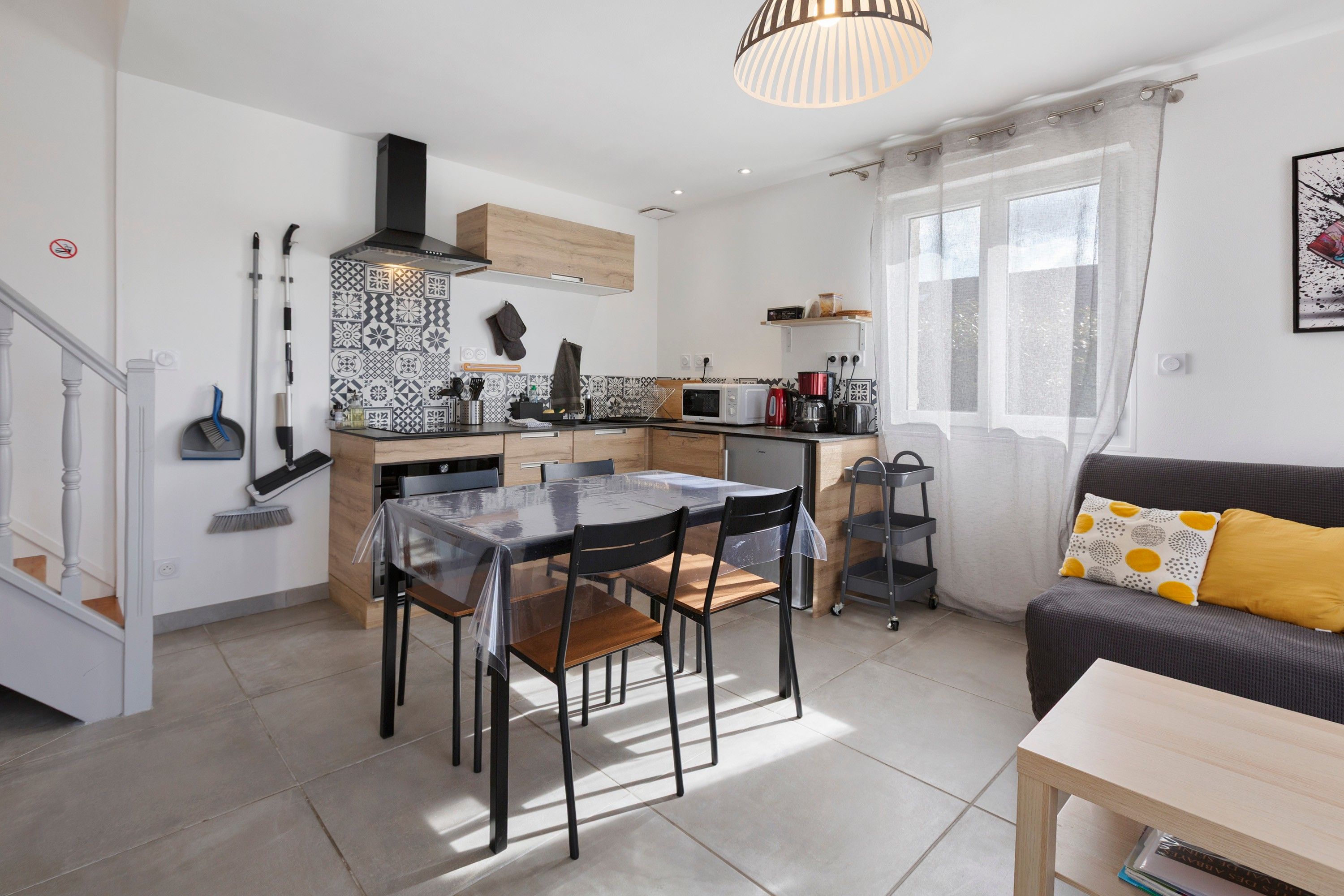 Una cocina moderna con zona de comedor, sofá y ventana con cortinas.