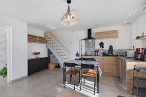 A modern kitchen with a dining area, a staircase, and a kitchen island. - 2-Star Holiday Home “L'Austreberthe des Abbayes du Val de Seine” (Sainte-Marguerite-sur-Duclair)