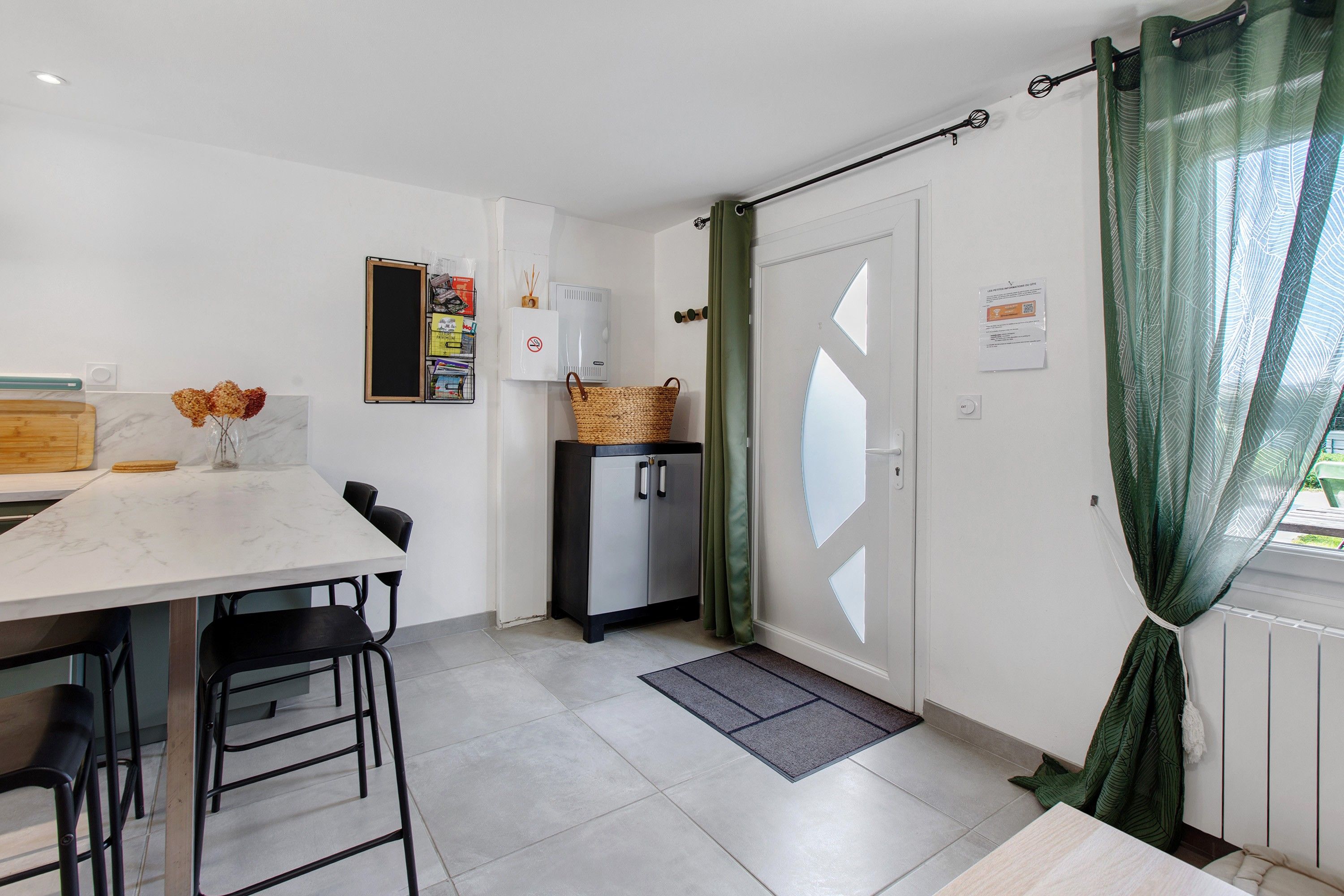 A compact kitchen with a dining table, chairs, a refrigerator, and a small cabinet.