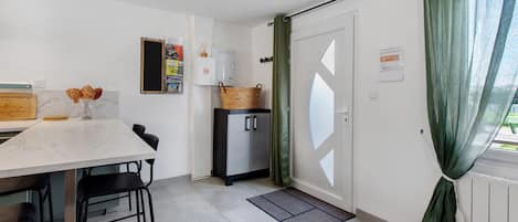 Una cocina compacta con una mesa de comedor, sillas, un refrigerador y un pequeño armario.