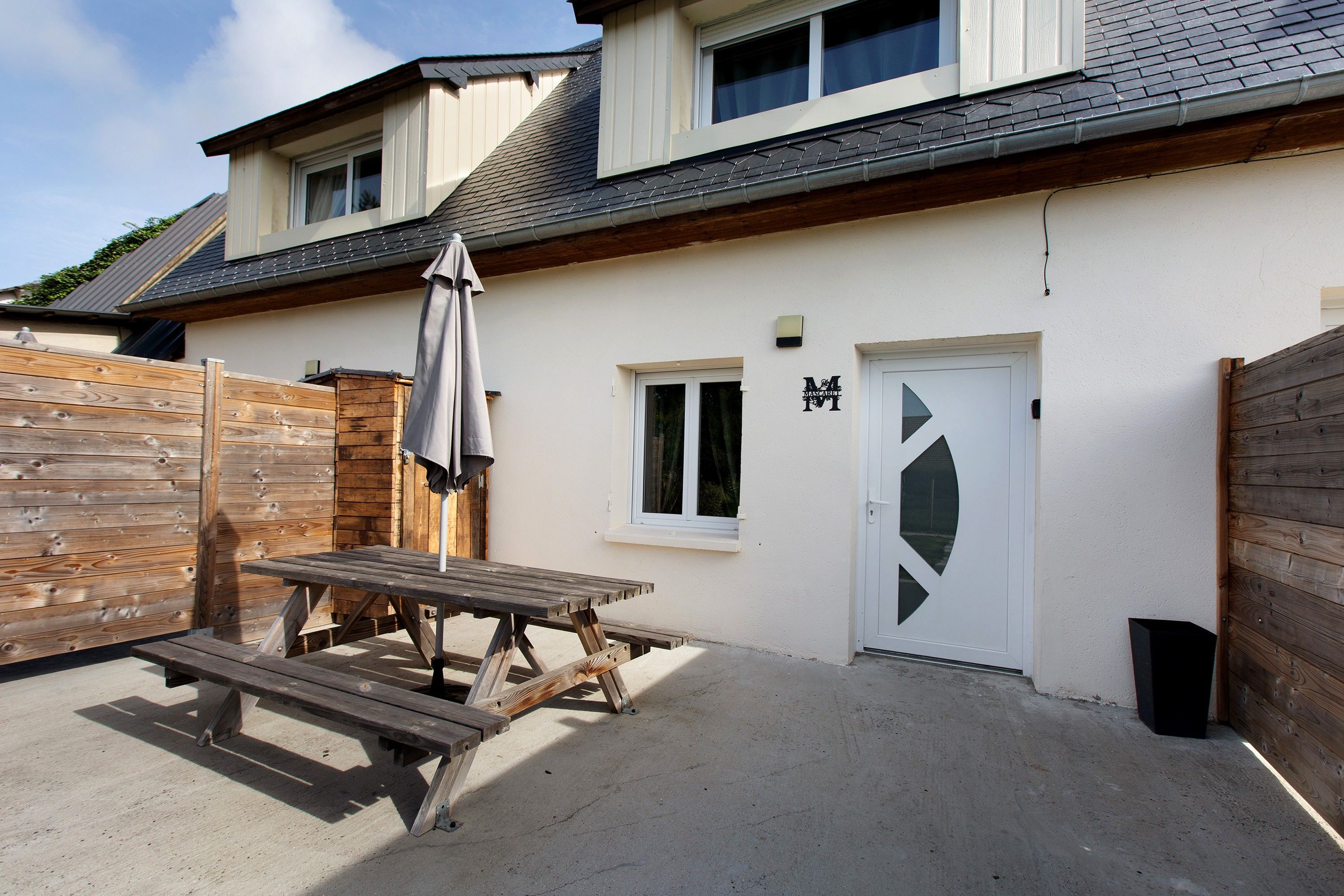 A house with a patio, a wooden fence, and a door with a window.