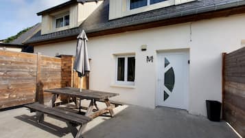 Une maison avec un patio, une clôture en bois et une porte dotée d’une fenêtre.