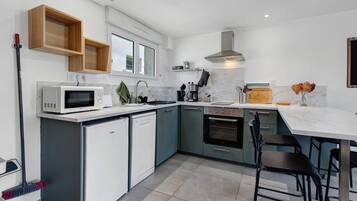 Een moderne keuken met een geïntegreerde vaatwasser, een magnetron, een fornuis en een koffiezetapparaat.