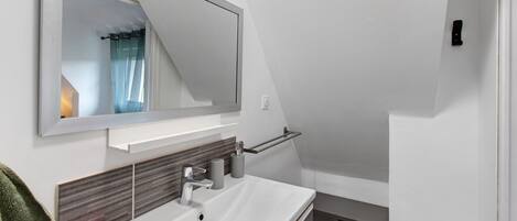 A modern bathroom with a white sink, a mirror, and a towel rack.