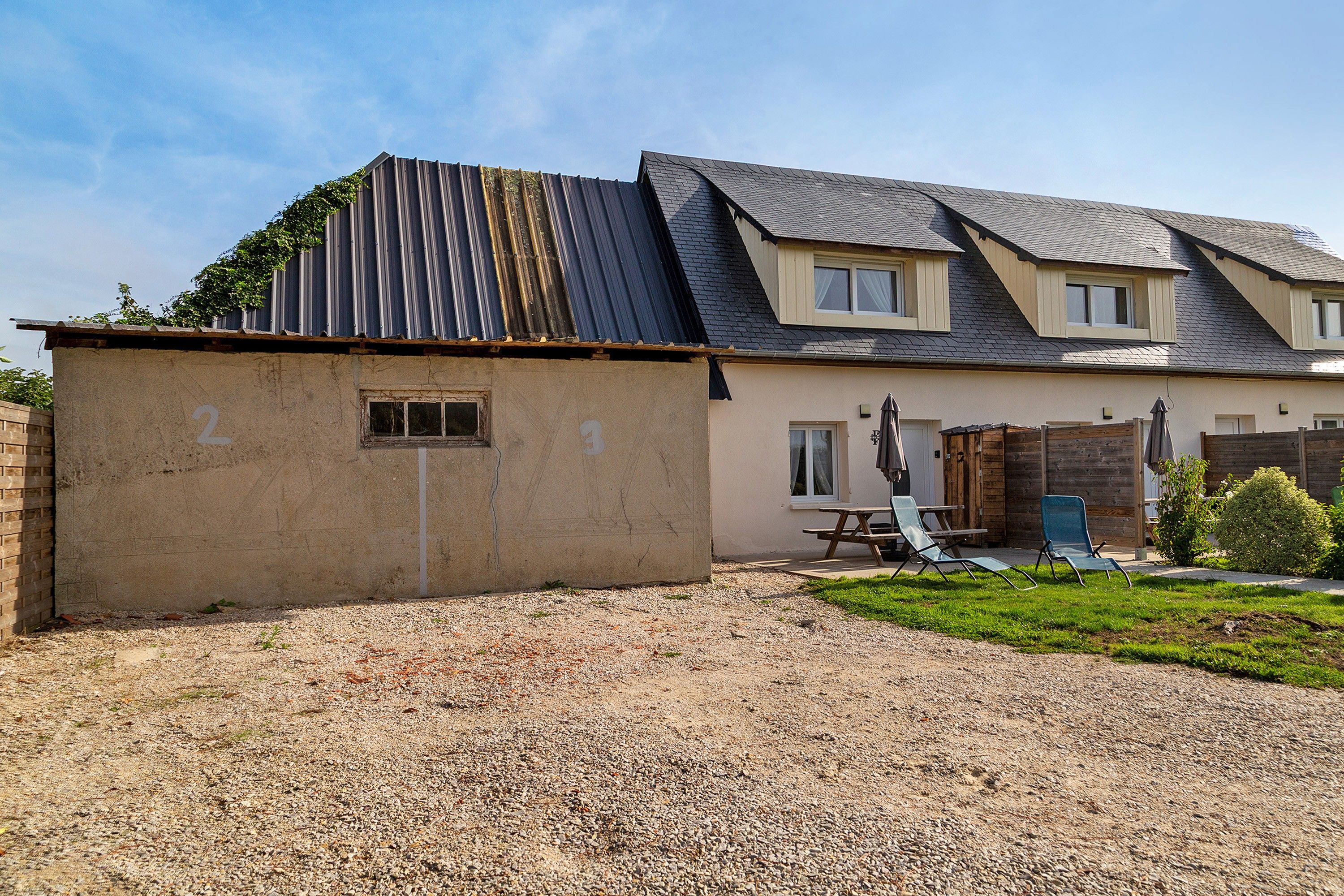 A two-story house with a gravel driveway and a fenced backyard.