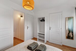 Une chambre à coucher comprenant un lit, un luminaire suspendu, une armoire avec des étagères et une porte.