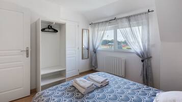Ein Schlafzimmer mit einem Bett, einem Kleiderschrank, einer Heizung und einem Fenster mit Vorhängen.