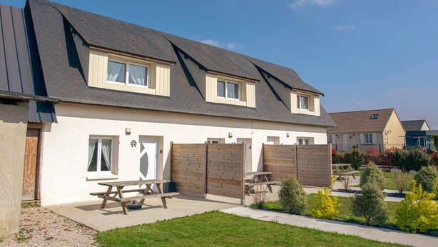 Une maison à deux étages, avec un toit en pente, une porte d’entrée et un portail de garage visible.