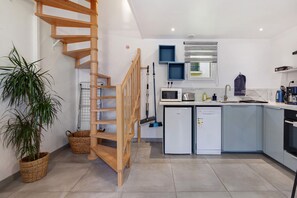 Una cucina moderna con una scala a chiocciola in legno, un forno a microonde, una lavastoviglie e un lavello.