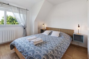 Una camera da letto con un letto, due comodini, una finestra con tende e vista su alberi.