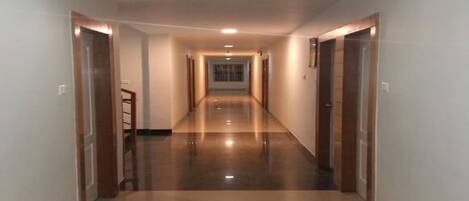 A long, well-lit corridor with a shiny floor, leading to a door at the end.