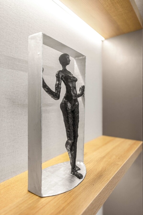 A sculpture of a human figure in a reflective box on a wooden shelf. - Tide Hotels and Resorts (Abuja)