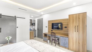 Een moderne slaapkamer met een bed, bureau, stoel, kledingkast en een televisie aan de muur.