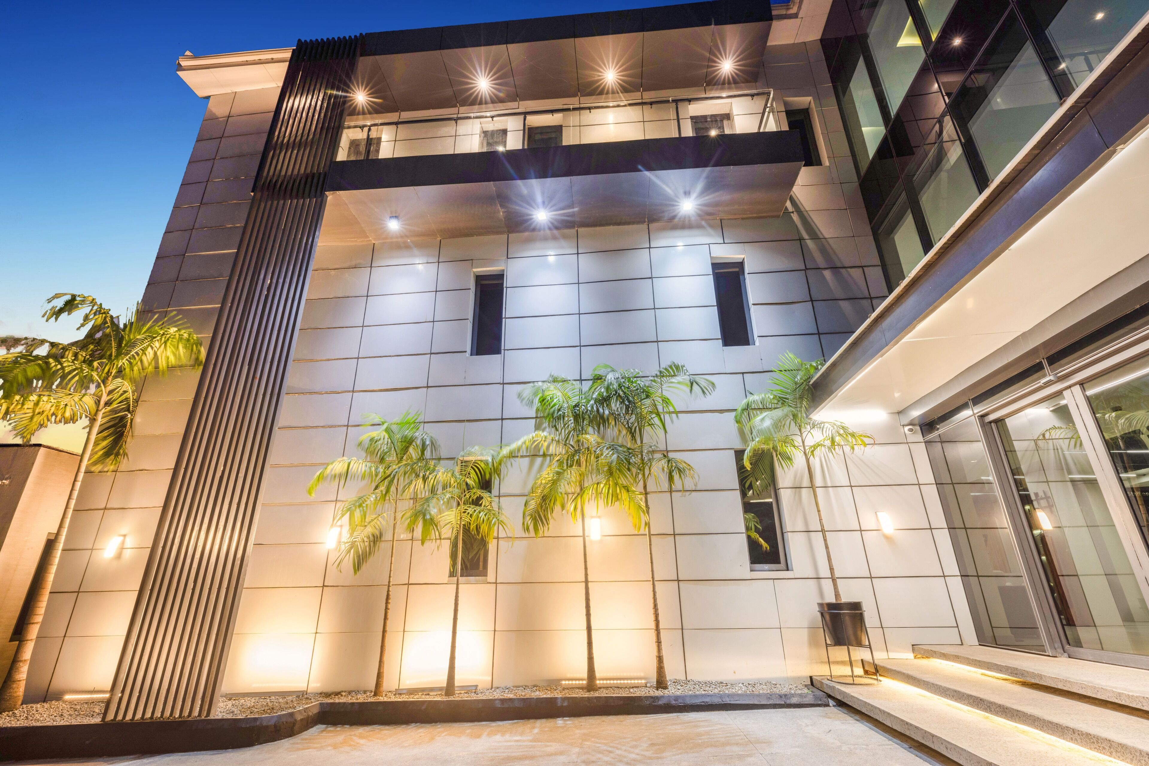 A modern building with a flat roof, large windows, and a well-lit entrance.