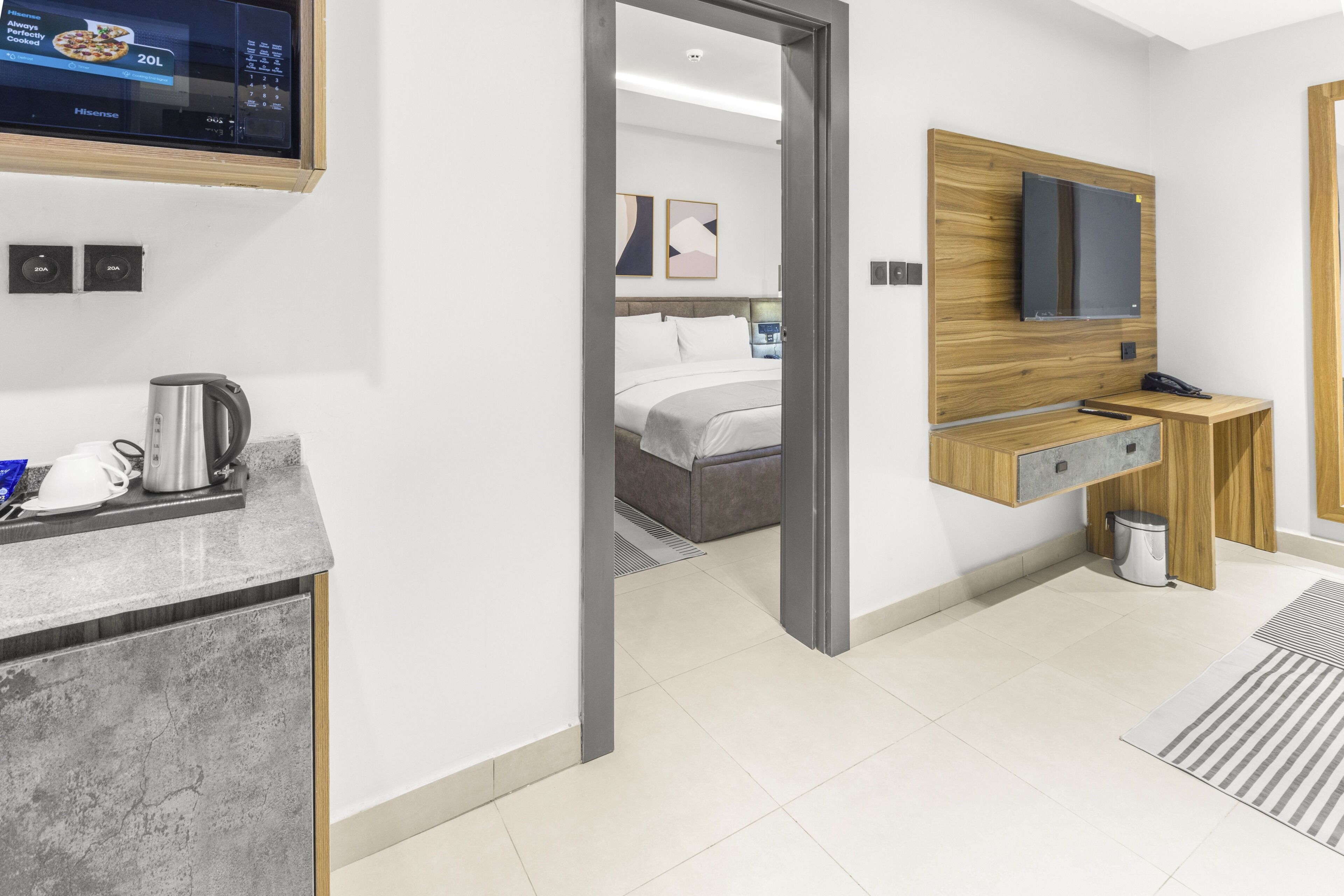 A modern hotel room with a bed, a TV, a desk, and a coffee maker.