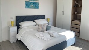 Un dormitorio con cama, mesitas de noche, un armario y una obra de arte en la pared.