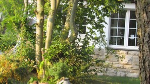 A stone building with a window, surrounded by trees and greenery. - Alte Schule Altefeld, Holiday Apartment for 4 Guests (70 m²) (Herleshausen)