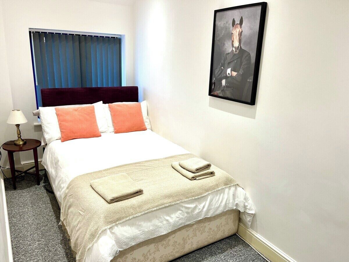 A neatly made bed with a headboard, a bedside table with a lamp, and a framed picture on the wall.