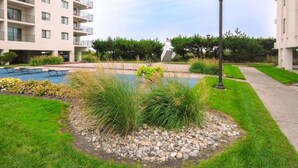 Un edificio residencial con piscina, jardín ajardinado y farola.