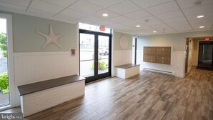 Zona de recepción con un banco, una decoración de estrella de mar, un tablón de anuncios y una puerta que da al exterior.