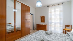 Un dormitorio con un armario grande, una cama con toallas dobladas, un aparador, una silla y un espejo.