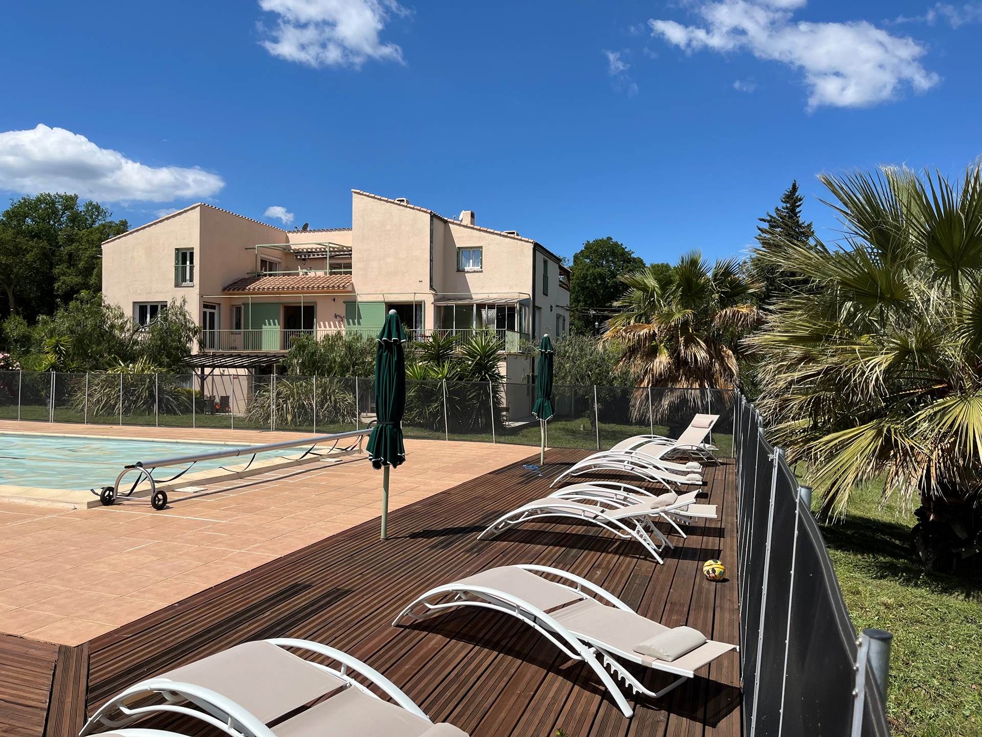 A poolside area with lounge chairs, a pool, and a building with a tiled roof.