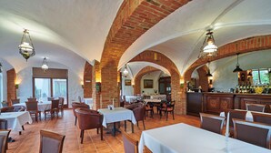 Un restaurant avec des arches en briques, des tables blanches et des lampes suspendues.