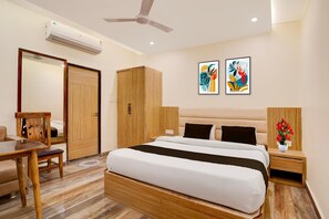 Ein Hotelzimmer mit einem Bett, einem Schreibtisch, einem Stuhl, einem Kleiderschrank und zwei an der Wand befestigten Kunstwerken.