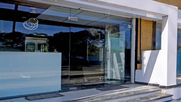 A modern building entrance with glass doors, a wooden wall, and a clear view of the street outside. - Super Townhouse Mahamrityunjay Dwar (Ujjain)