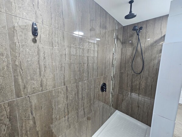A bathroom with a shower area, tiled walls, and a ceiling-mounted showerhead.
