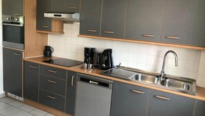 A modern kitchen with grey cabinets, a dishwasher, a coffee maker, and a stainless steel sink. - Countryside Stay With Terrace (Heers)