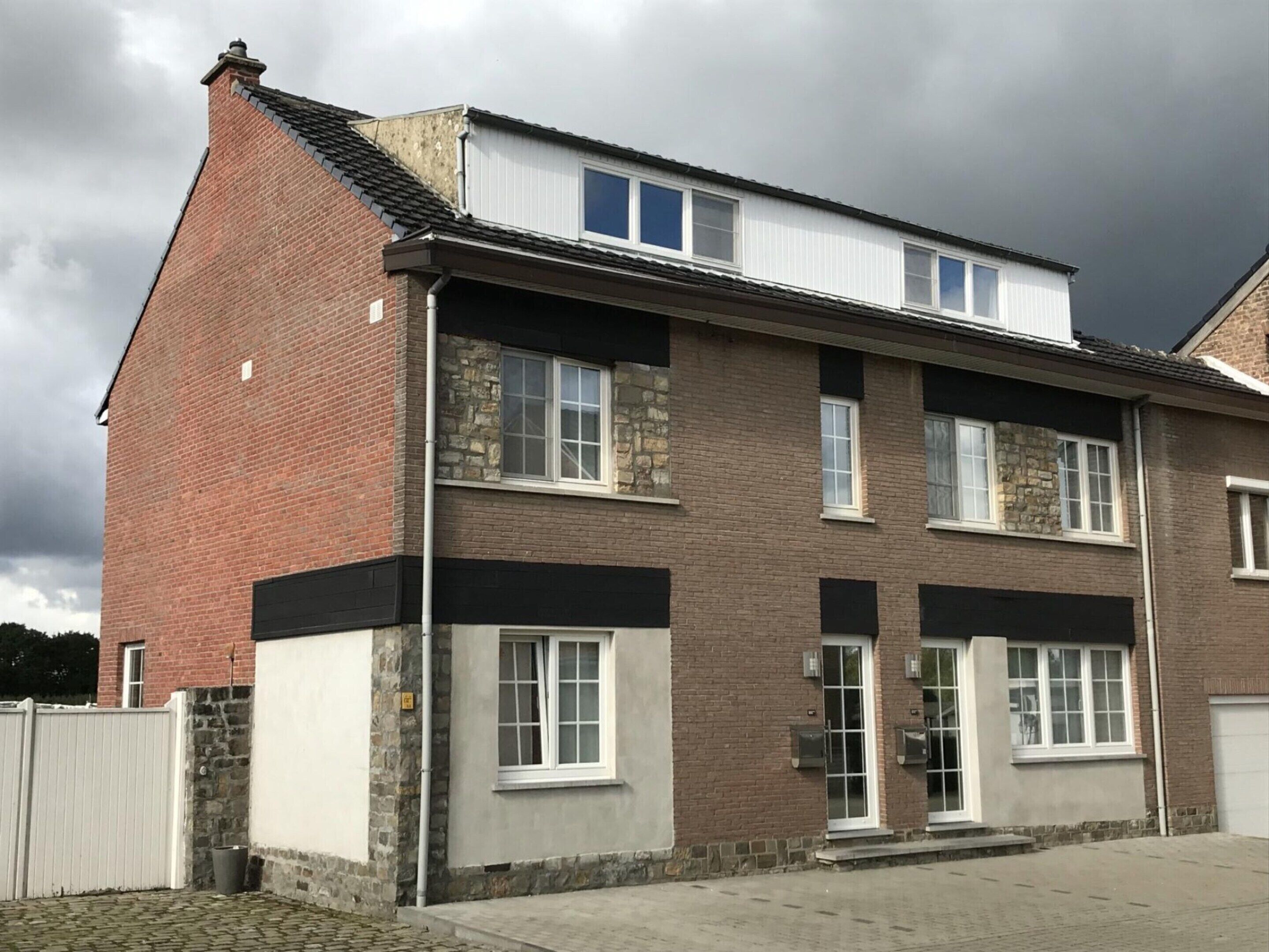 Een gebouw met twee verdiepingen, een bakstenen gevel, stenen accenten en een plat dak.