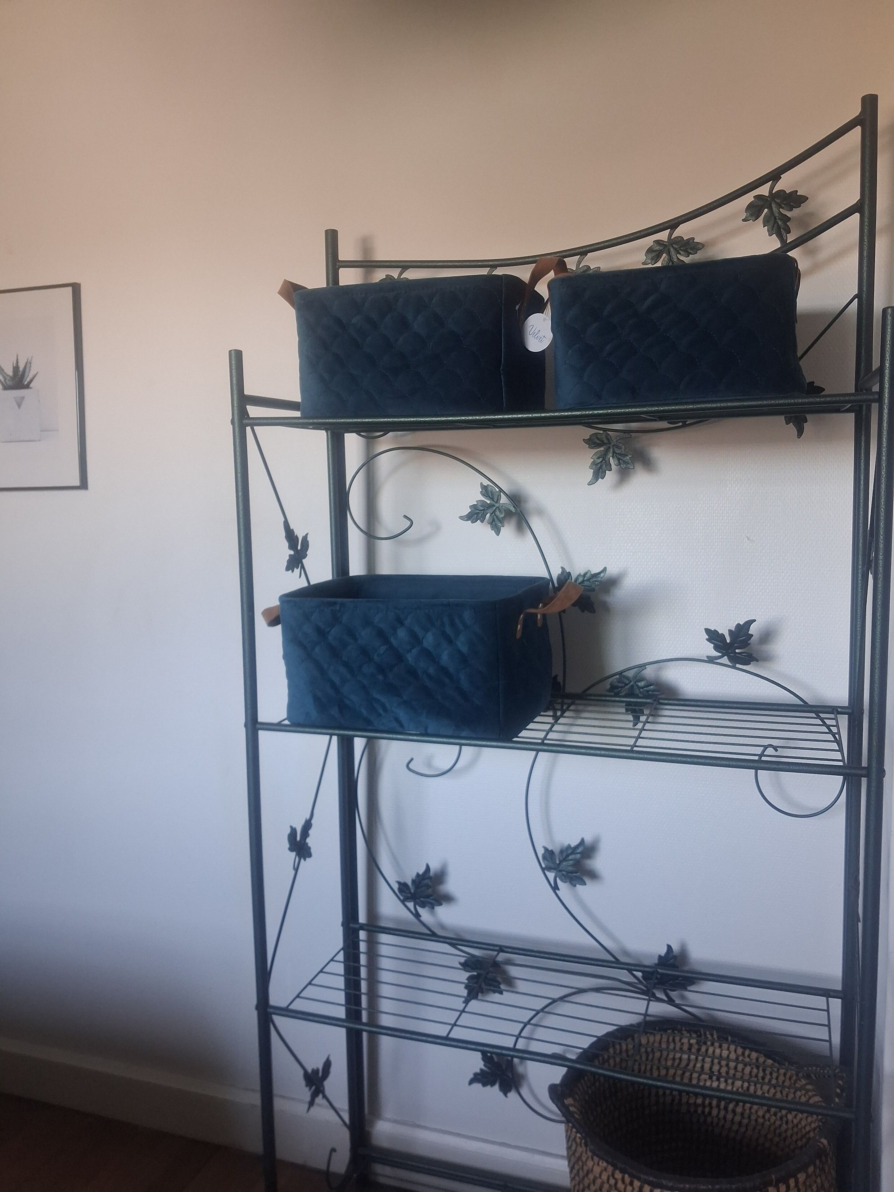 A metal shelving unit with three blue storage bins and a wicker basket.