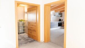 A modern kitchen with stainless steel appliances, a wooden door, and a concrete floor. - Experience beautiful high-ceilinged living rooms with exposed roof trusses! (Wildschönau)