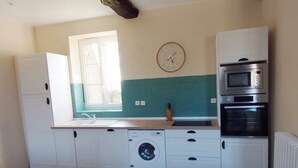 Una cuina compacta amb rentadora, forn i un rellotge a la paret.