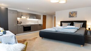 Une chambre moderne avec un grand lit, des tables de chevet et un coin cuisine.